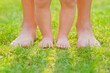Young adult mother and baby standing together with barefoot on fresh green grass at park in beautiful warm sunny summer day. Front view. Closeup.