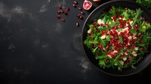 Fresh Spring Salad With Rucola, Feta Cheese, Red Onion And Pomegranate Seeds In Black Bowl On Chalkboard Background With Free Text Space.