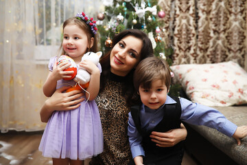 A young girl helps her mother to decorate the family Christmas tree. Family, winter holidays and people concept - happy mother and little daughter at home.