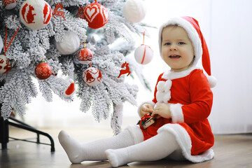 Wall Mural - Merry bright christmas. Lovely baby enjoy christmas. Childhood memories. Santa girl little child celebrate christmas at home. Family holiday. Girl cute child cheerful mood play near christmas tree.