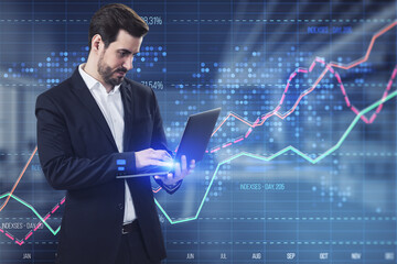 Poster - Attractive young businessman using laptop with creative business graph with index and grid on blurry office interior background. Stock market and financial statistics concept. Double exposure.