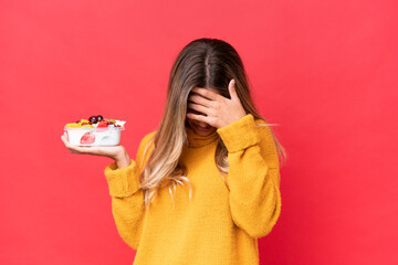 Wall Mural - Young pretty Uruguayan woman holding a bowl of fruit isolated on red background with tired and sick expression