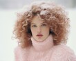 © Glittering Humanity - A striking winter portrait of a beautiful woman with curly hair and a pink sweater, her hairpiece adorned with delicate ringlets, her lips painted with a bold hue, style as she stands in the snow