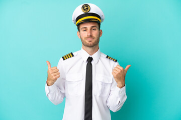 Wall Mural - Airplane caucasian pilot isolated on blue background with thumbs up gesture and smiling