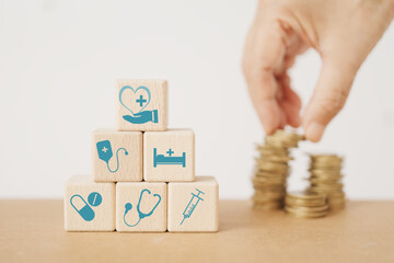 Wall Mural - Wood cube blocks with healthcare medical icon , blurred hand and stack of coins for  health insurance, wellness, wellbeing concept
