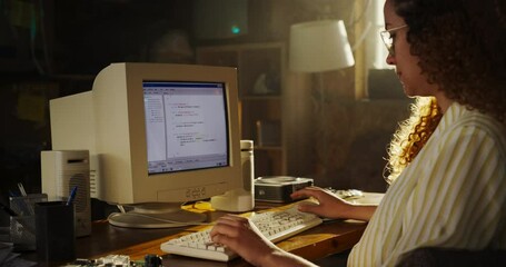 Poster - Side View Of Hispanic Female Software Engineer Programming on Old Desktop Computer In Retro Garage. Focused Woman Starting Tech Startup Company In Nineties. Coding Innovative Online Service At Home.