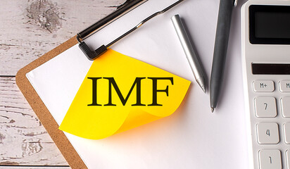 IMF word on yellow sticky with calculator, pen and clipboard