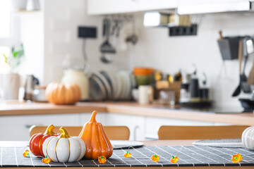 Wall Mural - Decor of white classic kitchen with pumpkins, garlands, latern for Halloween and harvest with figurine of house. Autumn mood in home interior, modern loft style. real estate, insurance, mortgage