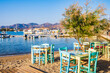 Tables and chairs in typical Greek taverna restaurant in Pollonia port, Milos island, Cyclades, Greece