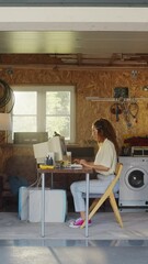 Fototapete - Vertical Screen: Hispanic Female Developer Programming On Old Desktop Computer In Retro Garage With Random Appliances. Young Woman Working On Innovative Online Service Startup Company In Nineties.