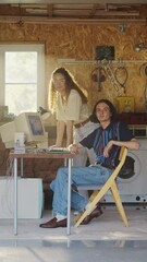 Fototapete - Vertical Screen: Caucasian Male Software Developer And Hispanic Female Designer Looking At Camera And Smiling In Retro Garage With Old Computer. Startup Founders Working On Online Service In Nineties.
