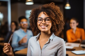 Wall Mural - A confident young African businesswoman wearing glasses pictured alongside a group of office workers during a meeting.