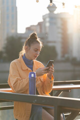 Poster - A young woman with a smartphone in her hands on the street in autumn.