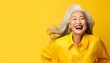 happy smiling beautiful elderly asian woman on yellow solid background with copy space