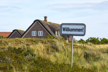 Wall Mural - Schild Willkommen auf Düne vor Reetdachhaus