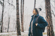 © olezzo - Adult mature woman breathes fresh air and enjoys the snowfall in the winter forest