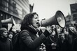© Rzk - a woman shouting through megaphone on a workers environmental protest in a crowd in a big city. black and white documentary photo