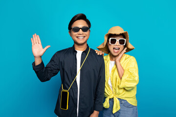 Cheerful asian couple in hat with open mouth, smartphone with empty screen, enjoy vacation