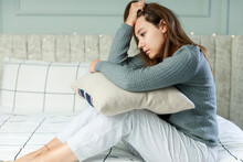 Young Woman Sitting With A Pillow In Bed. She Feeling Sad, Disappointed In Love In The Bedroom