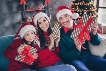 Wall Mural - Portrait of cute sweet small girl peaceful cheerful parents sitting couch hold festive giftbox house indoors