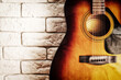 Grunge image of the old acoustic guitar in the interior with white brick wall. Musical instruments and music backgrounds. Copy space for text