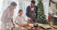 Happy Family During Christmas: Portrait Of Little Cute Girl Learning How To Make Cookies And Celebrating Her Achievement With Her Parents. Cute Family Preparing Together For Holiday Dinner