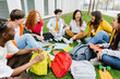 © Xavier Lorenzo - College student group sitting together at campus grass. Diverse millennial classmates relaxing after class outdoors. Friendship and education lifestyle concept.