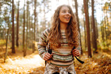 Fototapeta  - Beautiful young tourist with a backpack is having fun in the autumn forest, throwing fallen leaves. Woman walks along a colorful path in the forest. Freedom, travel.