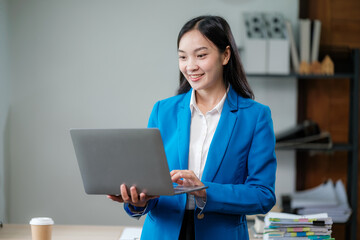 Wall Mural - Professional business woman manager executive wearing suit looking at laptop computer technology in office working on digital project sitting at desk.