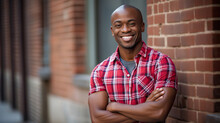 African-American Man In A Red And White Checkered Shirt, Leaning Against A Brick Wall