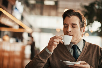 Wall Mural - Young businessman having a cup of coffee in a cafe decorated for christmas and the new year holidays