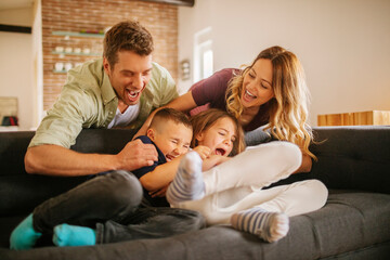 Wall Mural - Happy young family embracing each other on the couch at home