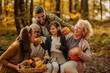 © bernardbodo - Happy family sitting in the woods holding pumpkins and eating corn