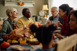 © Drazen - Happy multiracial extended family enjoying in conversation during Thanksgiving meal at dining table.