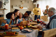 © Drazen - Cheerful multiracial family has fun while gathering for Thanksgiving at home.