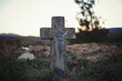 Old tombstone with Jesus Christ on traditional European cemetery. Close up of aged cross tomb stone on grave yard in the evening. Autumn scene. Single cross tombstone alone