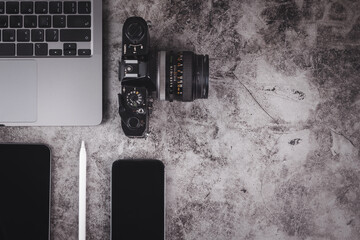 Top view of grunge cement table with computer laptop, camera, smartphone, tablet and digital pen in concept of digital content creator, photographer and freelancer.