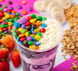 close up of acai or açaí smoothie cup with topping confetti and powdered milk in colorful background
