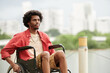 © DragonImages - Portrait of smiling pensive Black man sitting in wheelchair and looking away