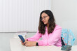 © Thales - Portrait of a psychopedagogue, wearing pink clothes, in her office, sitting, looking at the appointments scheduled on her cell phone. Helps with school performance.