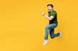 © ViDi Studio - Full body side profile view young sporty cool fun happy man he wearing green t-shirt casual clothes jump high run fast hurry up isolated on plain yellow background studio portrait. Lifestyle concept.