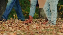 Cheerful Family Playing With Autumn Leaves, Walking In Nature With Child. Family, Child, Mother, Father Are Walking In An Autumn Park, Kicking Yellow Dry Leaves With Their Feet. Family Outdoors. Legs