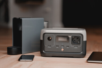 Coffee machine and portable power supply station on a wooden floor. Mobile device for charging the phones, laptops and kitchen appliances. Back up system solution for home.