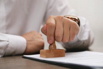 Man stamping document at wooden table, closeup