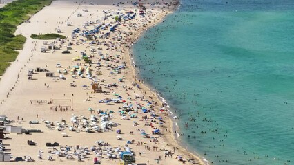 Wall Mural - Famous Miami beach with soft white sand in Florida, USA. Many people enjoying vacation time bathing in warm Atlantic ocean water and tanning under hot sun