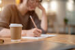 © bongkarn - Close-up image of a girl keeping her diary in a coffee shop, selective focus at a coffee cup.