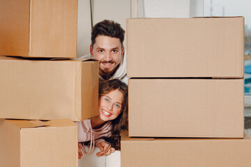 Happy young family couple man and woman portrait relaxing after moving cardboard boxes to new real estate apartment.