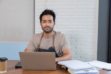 handsome indian male restaurant owner sit and looking at camera with confidence. man employee wearin