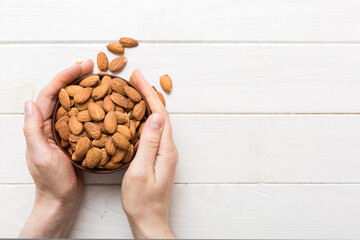 Wall Mural - Woman hands holding a wooden bowl with almond nuts. Healthy food and snack. Vegetarian snacked of different nuts