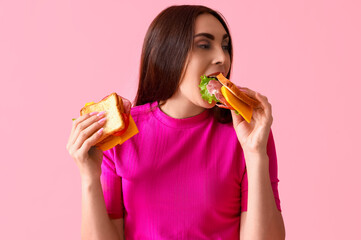 Canvas Print - Young woman eating tasty sandwich on pink background